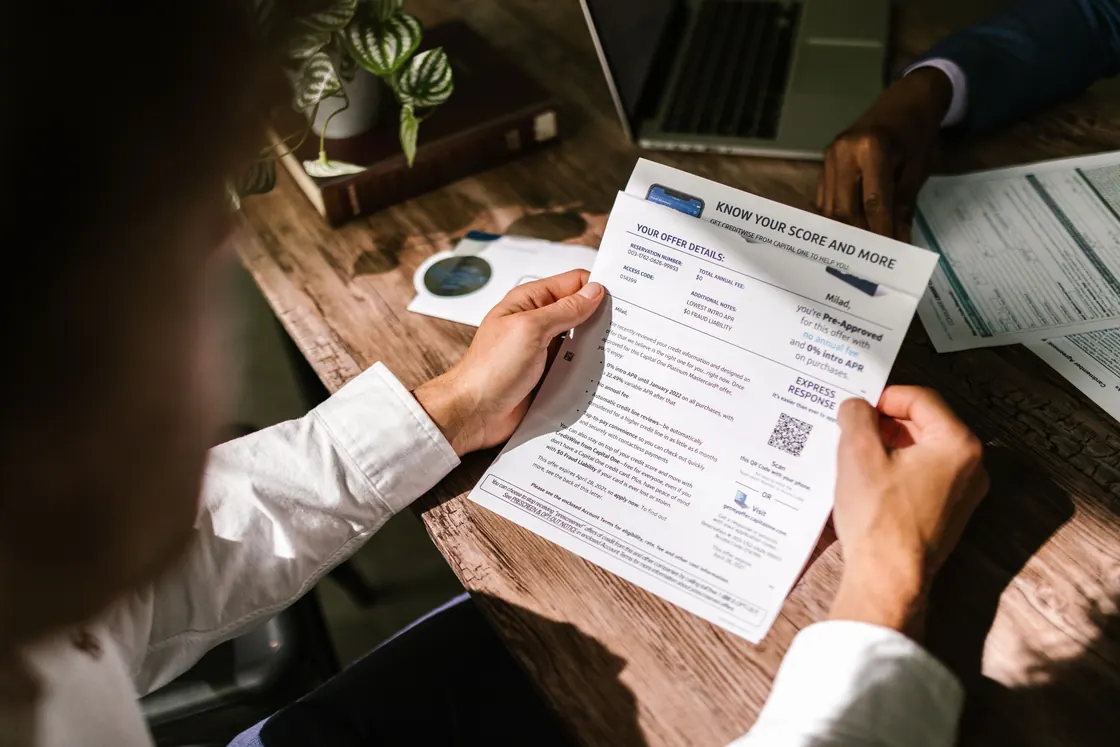 Un hombre revisa un documento financiero a la luz de la ventana.
