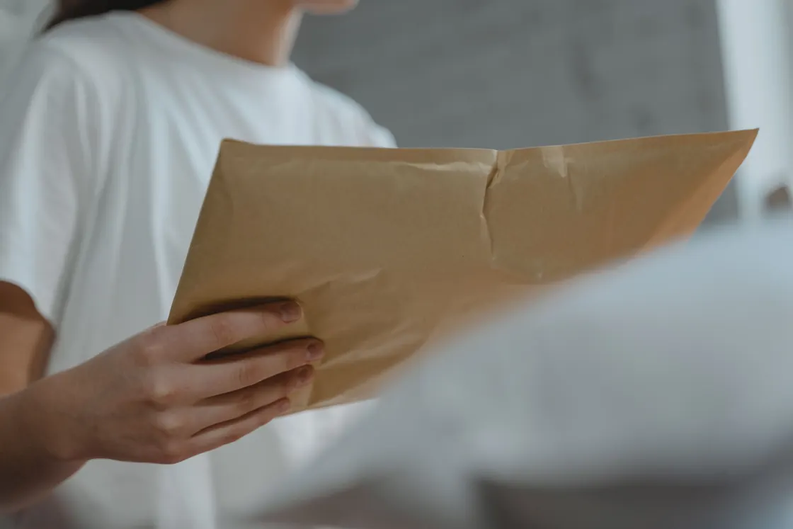 Una persona sostiene un sobre de papel listo para enviar por correo.