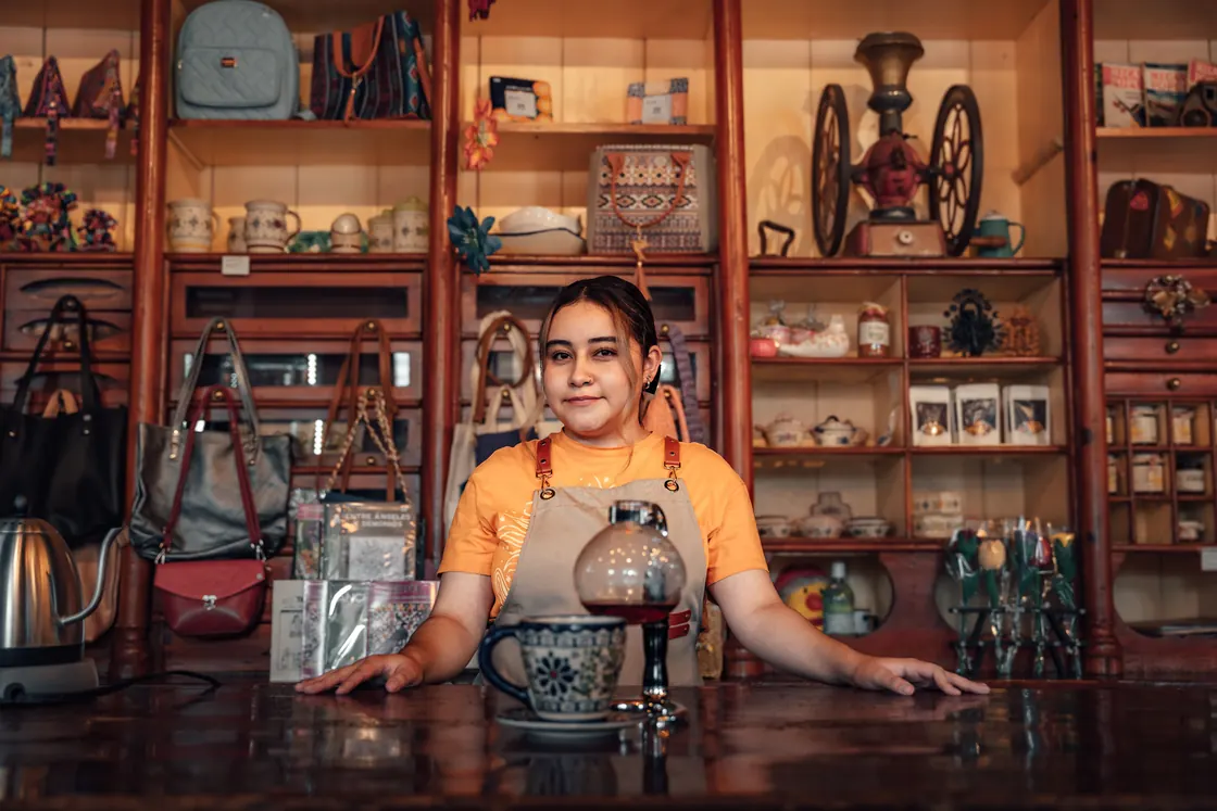 Una comerciante joven detrás del mostrador de su tienda, el tipo de persona que necesita saber qué institución le va a aceptar sus papeles.